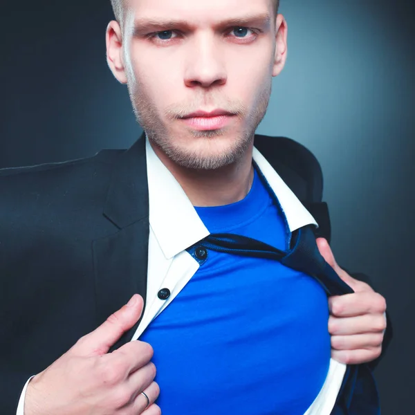 Joven hombre de negocios actuando como un súper héroe y rasgando su camisa, aislado sobre un fondo gris —  Fotos de Stock