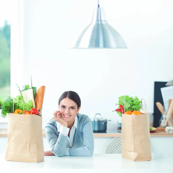 Smiling young woman in the kitchen near desk — Stock Photo, Image