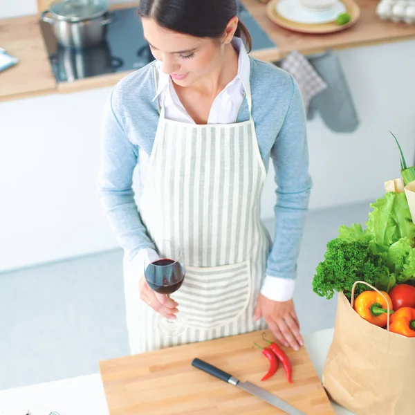 Frau mit Einkaufstaschen in der Küche zu Hause, neben Schreibtisch — Stockfoto