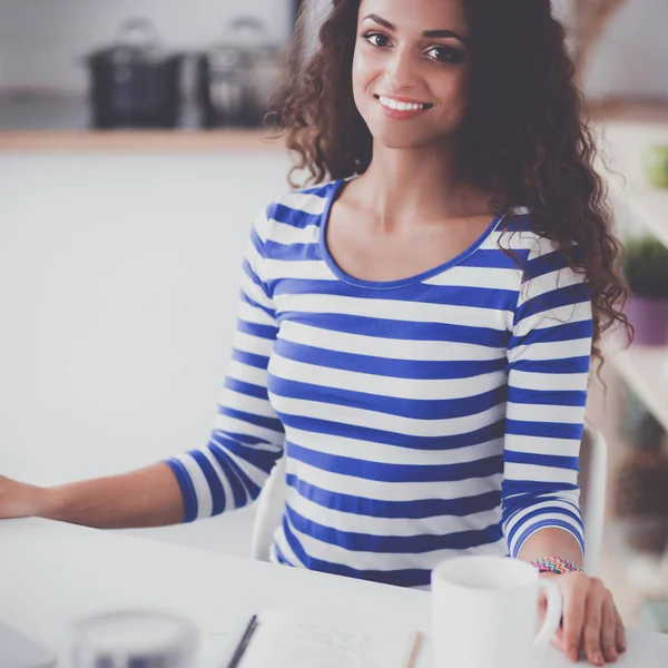 コーヒー カップと自宅の台所でラップトップを持つ若い女性の笑みを浮かべてください。 — ストック写真