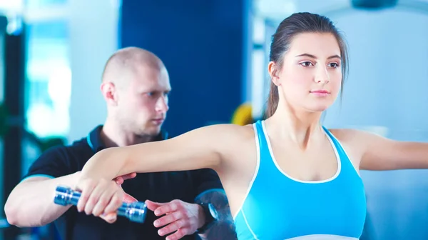 Hermosa mujer en el gimnasio haciendo ejercicio con su entrenador —  Fotos de Stock