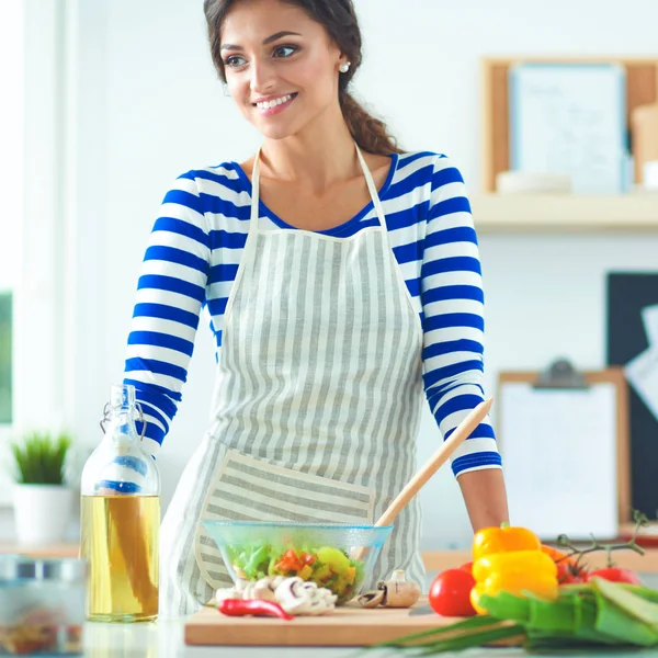 Smiling young woman  mixing fresh salad, standing near desk — Stock Photo, Image