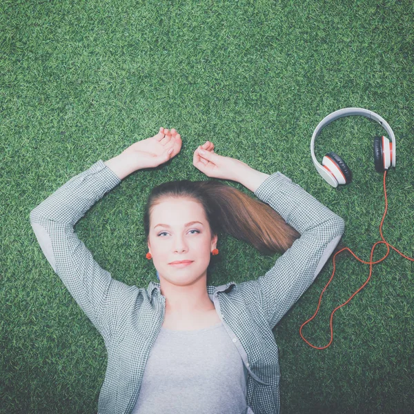 Relaxed woman listening to the music with headphones lying on grass — Stock Photo, Image