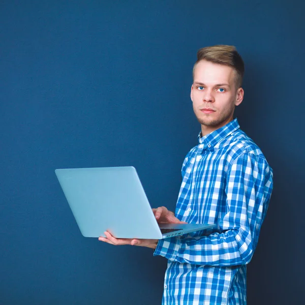 自信的年轻人用笔记本电脑站立在灰色背景的肖像 — 图库照片