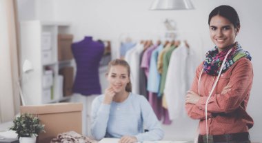 Ofis masasında çalışan genç, çekici bayan moda tasarımcısı, cep telefonuyla konuşurken çizim yapıyor.