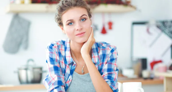 Smiling woman with cup of coffee and newspaper in the kitchen — Stock Photo, Image