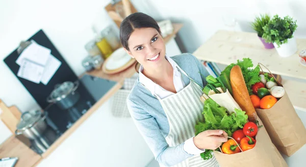 Mulher com sacos de compras na cozinha em casa, de pé perto da mesa — Fotografia de Stock