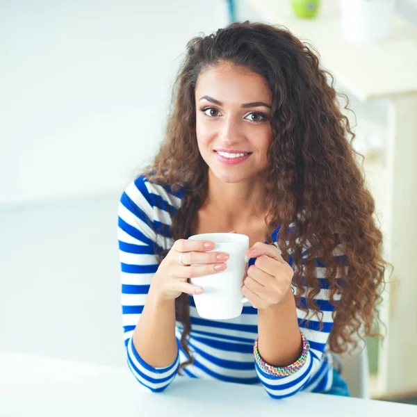 Портрет молодої жінки з чашкою на фоні інтер'єру кухні — стокове фото