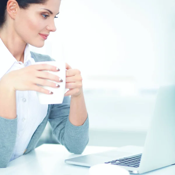 Junge Geschäftsfrau sitzt mit Tasse im Büro auf dem Schreibtisch — Stockfoto