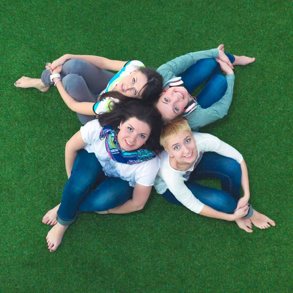 Group of smiling friends lying on grass in circle — Stock Photo, Image