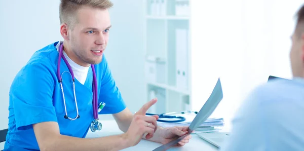 Portret van een lachende mannelijke arts met laptop aan het bureau in medisch kantoor — Stockfoto