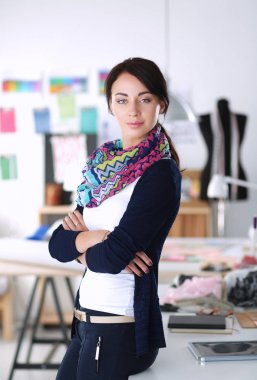 Güzel genç moda tasarımcısı stüdyoda duruyor.