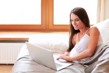 Evde dizüstü bilgisayar kullanan genç bir kadın.