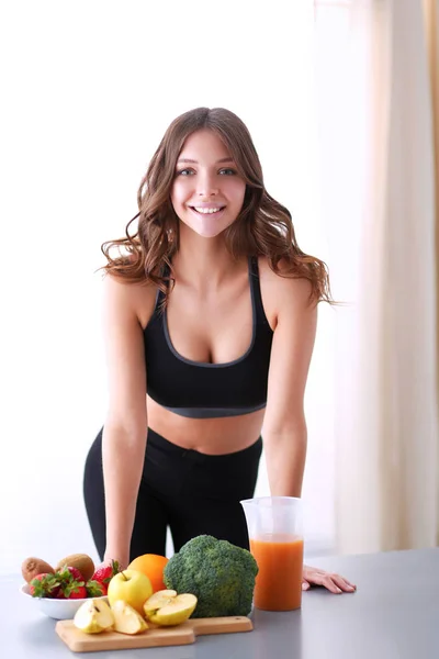 Jeune et belle femme debout près du bureau avec des légumes — Photo