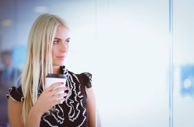 Ofiste bir fincan kahve ayakta tutan işkadını