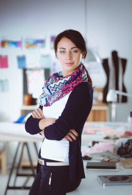 Güzel genç moda tasarımcısı stüdyoda duruyor.