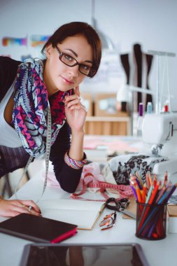 Genç terzi kâğıt üzerinde kıyafet deseni tasarlıyor.