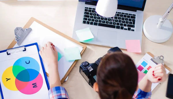 Vrouwelijke fotograaf zittend op het bureau met laptop — Stockfoto