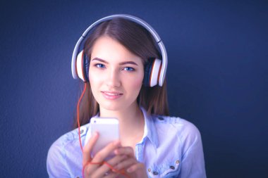 Duvara yakın katta oturan kulaklıklar ile gülümseyen kız