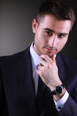 Gri arka plan üzerinde duran gülümseyen genç adam portresi