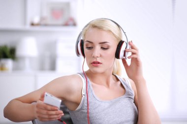 Evdeki genç ve güzel kadın kanepede oturup müzik dinliyor.