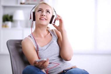 Evdeki genç ve güzel kadın kanepede oturup müzik dinliyor.