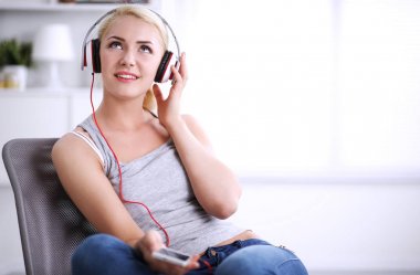 Evdeki genç ve güzel kadın kanepede oturup müzik dinliyor.