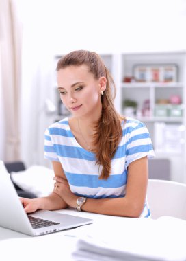 Elinde evrakları olan kadın masanın üstünde oturuyor.