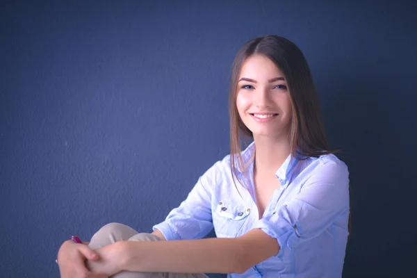 Mujer joven sentada en el suelo cerca de la pared oscura — Foto de Stock