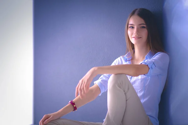 Young woman sitting on the floor near dark wall — Stock Photo, Image