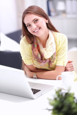 Elinde evrakları olan kadın masanın üstünde oturuyor.