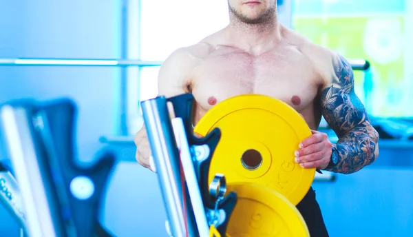 Junger Mann hebt mit Trainer die Langhantel in Turnhalle — Stockfoto