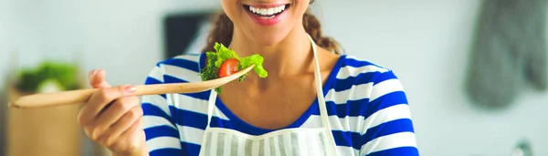 Ung kvinna äter färsk sallad i modernt kök — Stockfoto