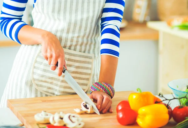 Ung kvinna skära grönsaker i köket — Stockfoto