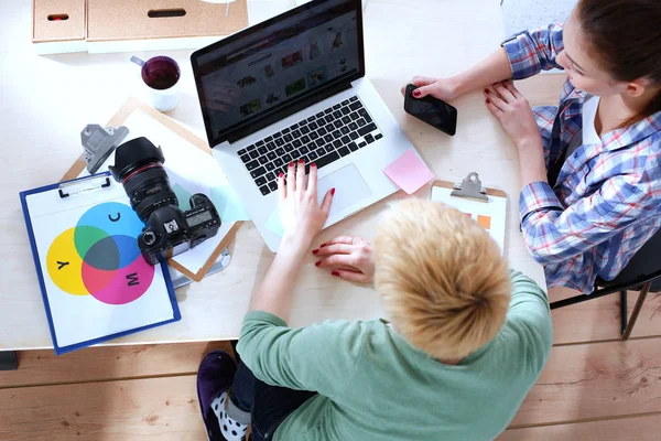 Vrouwelijke fotograaf zittend op het bureau met laptop — Stockfoto