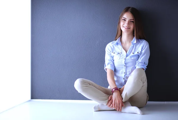 Mujer joven sentada en el suelo cerca de la pared oscura — Foto de Stock