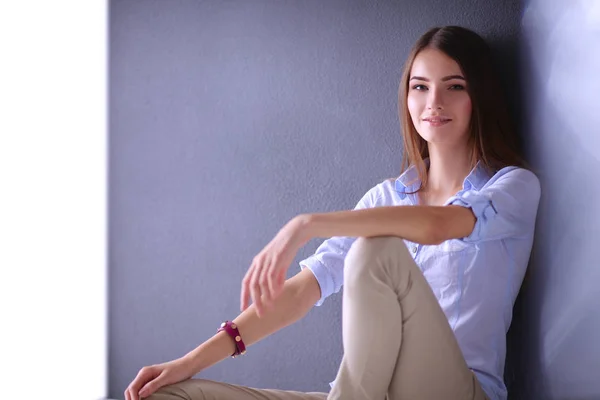 Wanita muda duduk di lantai dekat dinding gelap — Stok Foto