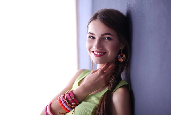 Jovem mulher sorridente de pé perto da parede escura — Fotografia de Stock