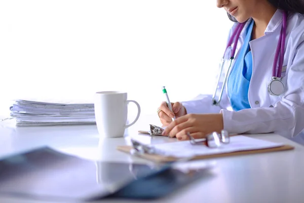Schöne junge lächelnde Ärztin sitzt am Schreibtisch — Stockfoto