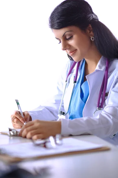 Bonito jovem sorridente médico feminino sentado na mesa — Fotografia de Stock