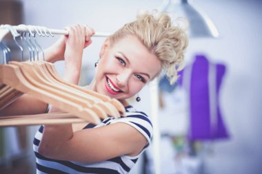 Raf ofiste askıları ile yakınındaki güzel genç stilist