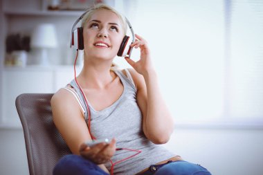 Evdeki genç ve güzel kadın kanepede oturup müzik dinliyor.