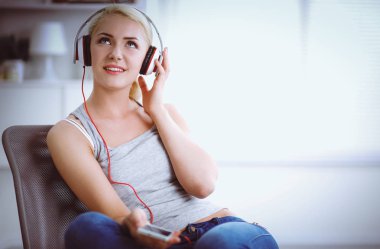 Evdeki genç ve güzel kadın kanepede oturup müzik dinliyor.