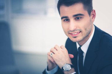 Genç işadamı ofiste çalışıyor, masada oturuyor.
