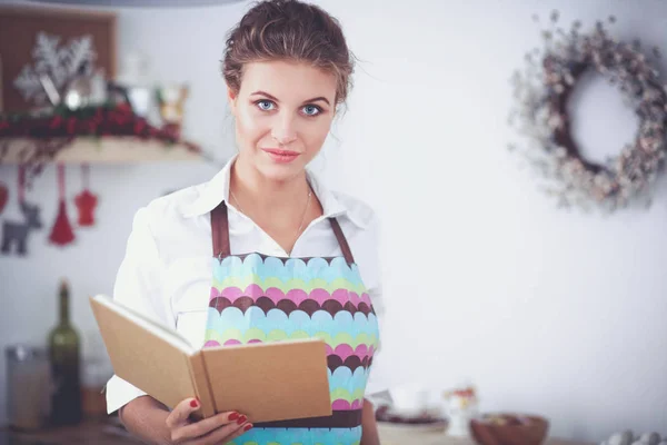 Jonge vrouw die kookboek leest in de keuken, op zoek naar recept — Stockfoto