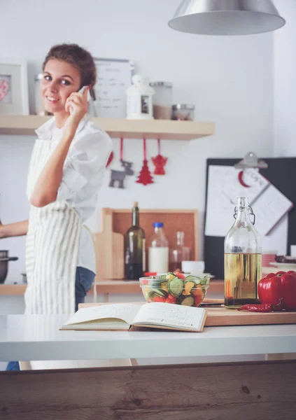 Portret van een lachende vrouw met telefoon in de keuken thuis — Stockfoto