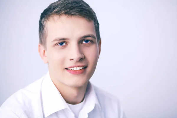 Retrato de jovem sorrindo sentado em fundo cinza — Fotografia de Stock