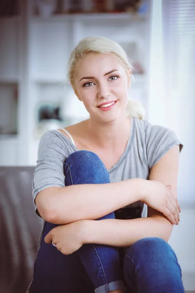 Jovem bela mulher sentada no sofá em seu quarto — Fotografia de Stock
