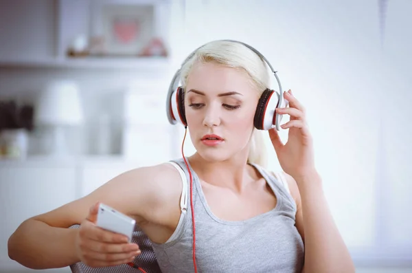 Jonge mooie vrouw thuis zitten op de bank en luisteren muziek — Stockfoto