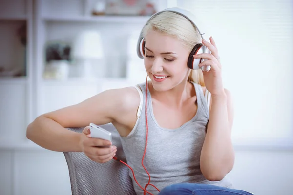 Joven hermosa mujer en casa sentada en el sofá y escuchando música —  Fotos de Stock